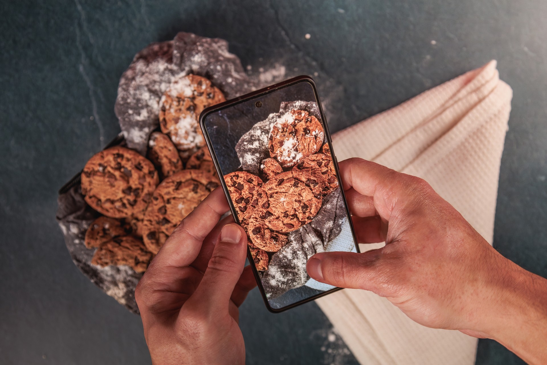 Man hands taking a picture of chocolate cookies to post it in social media.